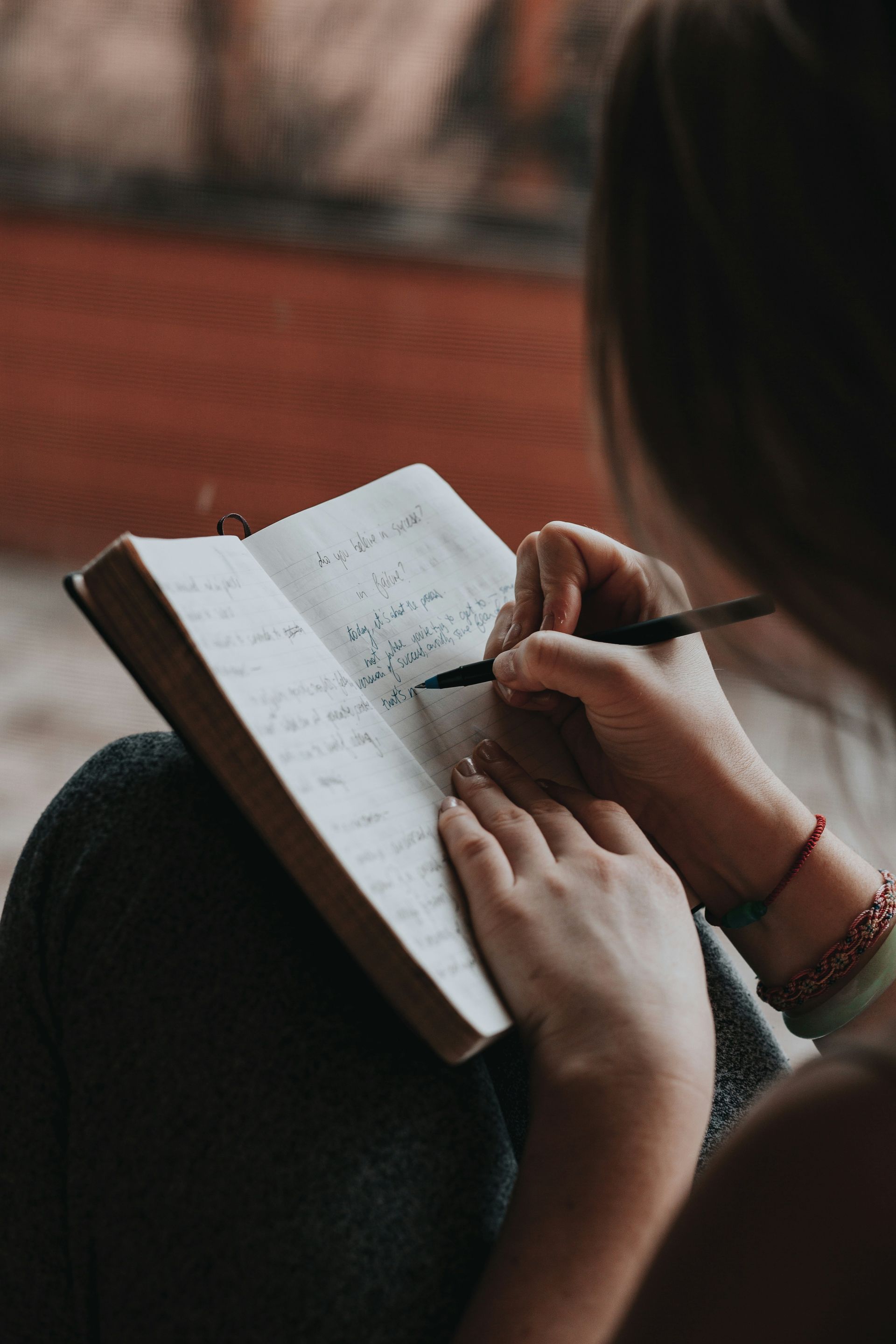 woman writing in notebook with pen